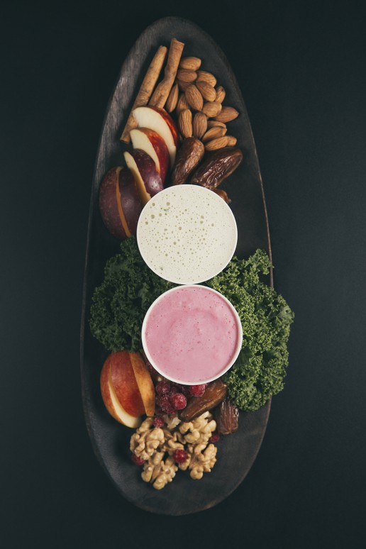 Kale and red berry smoothie on wooden tray with ingredients